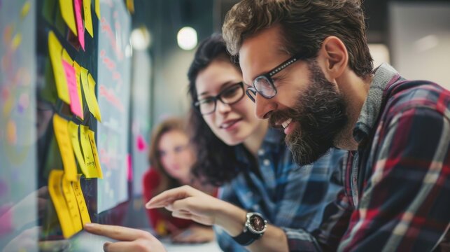 A creative team collaborates and brainstorms using colorful sticky notes on a glass board, fostering ideas and teamwork in a modern office.