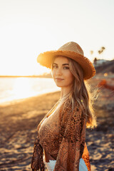 Portrait of one happy beautiful woman on the sand of the beach enjoying and having fun at the sunset of the day. Looking at the camera smiling..