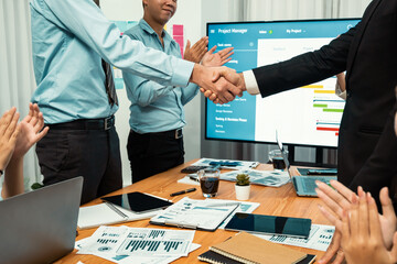 Cheerful meeting room, businesspeople celebrate with handshaking. Successful project was completed...