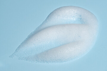 Skincare cleanser foam texture. Soap, shampoo, cleansing mousse bubbles swatch on blue color background. Face wash cosmetics