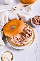 Hearty bagel burger with tuna and ricotta on a plate on the table vertical view