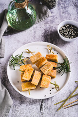 Pieces of delicious fried tofu soy cheese on skewers on a plate on the table vertical view