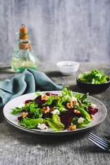 Delicious salad of beetroot, lettuce, nuts and ricotta on a plate on the table vertical view