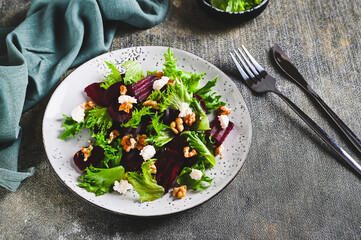 Beetroot salad with cheese, nuts and herbs on a plate on the table