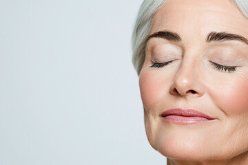 an elderly woman's face showing a serene, peaceful expression with closed eyes and a gentle smile