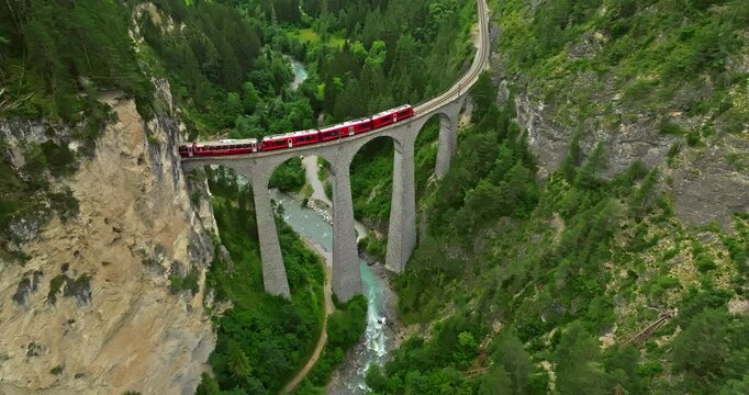 Railway scenic route in Switzerland. Express red swiss train in Swiss Alps. Landwasser Viaduct world heritage sight with luxury Glacier and Bernina express summer scenery