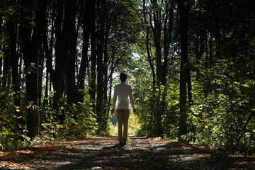 Authentic young man in white shirt walking in green autumn forest. Photo 15 September 2024 year.