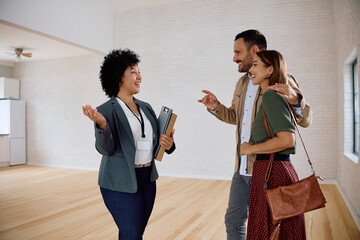 Happy couple talking to real estate agent while looking for new apartment.