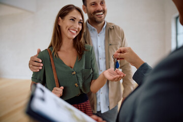 Happy woman and her husband getting keys from real estate agent while buying  new apartment.
