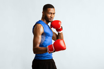 Professional Box Concept. Muscular athletic black boxer showing defending pose, yellow studio wall,...