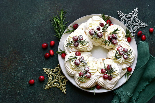 Christmas meringue cake Pavlova with cranberry and rosemary . Top view with copy space.