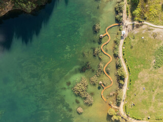 Aerial drone photo of Quarry turquiose lake colour, open pit mining in Park Grodek, Jaworzno. Poland. Turquiose Water and Wooden Bridge on lake. Polish Maldives Park Grodek in Jaworzno from drone.