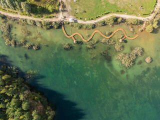 Aerial drone photo of Quarry turquiose lake colour, open pit mining in Park Grodek, Jaworzno. Poland. Turquiose Water and Wooden Bridge on lake. Polish Maldives Park Grodek in Jaworzno from drone.