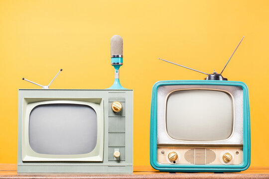 Retro TV set and microphone front yellow background. Vintage style filtered photo