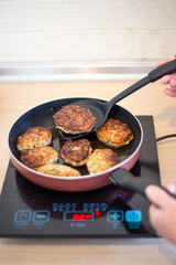 Cooking. A frying pan is on an induction cooker, in which meat patties are fried.