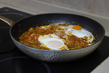 Vegetable ratatouille with fried egg on top, cooking in a pan. Spanish food concept.