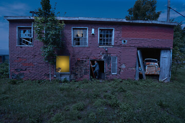 Spooky abandoned house under moonlight, with a man climbing a ladder, and an afraid person in a window