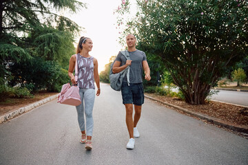 Happy couple of athletes going on sports training in park.