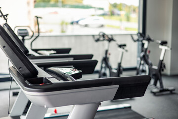Close-up of gym machines for cardio and resistance, including treadmills and spin bikes