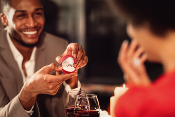 Valentine's Day Proposal. Happy Afro Man Giving His Girlfriend Engagement Ring Asking To Marry Him During Romantic Date In Restaurant