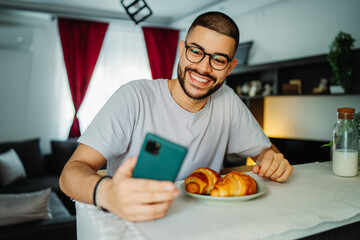 Young caucasian man eating croissant for breakfast