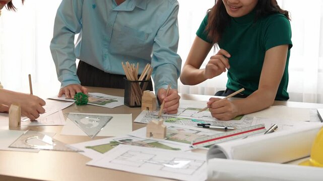 A video of architect use measurement tools and pencil to measure blueprint. Architect design house construction on a table at studio, with architectural plan scattered around. Focus hand. Delineation.