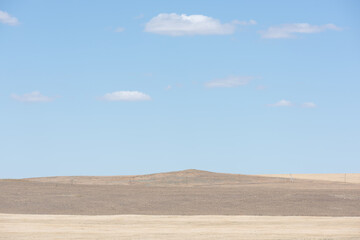 Low mountains in the steppe, blue sky and clouds