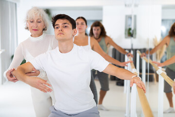 Fototapeta premium Diligent middle-aged man doing choreography with ballet master in training area during workout classes