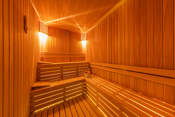 Interior of the Finnish sauna, classic wooden sauna with hot steam. Sauna room at hotel SPA center. Wooden interior baths, wooden benches and sun loungers sauna accessories, spa complex.