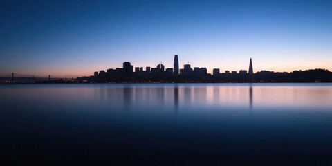 Fototapeta premium A stunning view of a city skyline at dusk with the sky painted in gradient colors, reflecting perfectly onto the calm water below, capturing an urban serenity and peace.