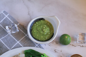 Thai spicy seafood dipping sauce eat with delicious seafood in white bowl with green lime on table. 