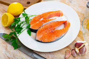 Salmon slice on plate with garlic, herbs and lemon. Rodajas de salmon