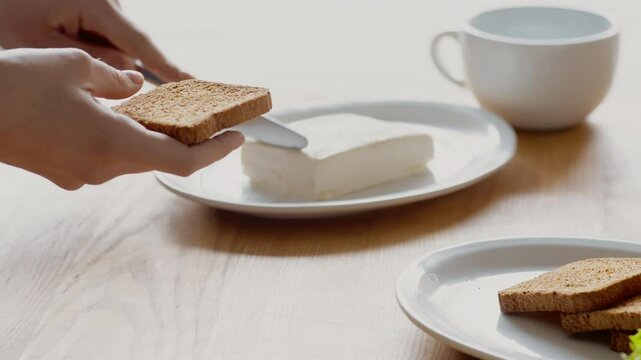 Healthy breakfast. Woman spreading fresh butter on rye bread toast, close up