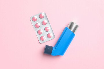 Asthma inhaler and pills on pink background, flat lay
