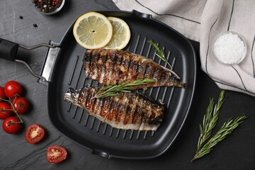 Delicious grilled mackerel, rosemary and lemon in pan on dark textured table, flat lay