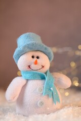 Funny snowman figure on artificial snow against blurred lights