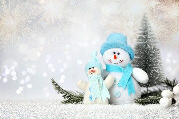 Cute snowmen against blurred Christmas lights, bokeh effect. Space for text