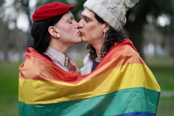 Transgender women wrapped in the LGBT flag kissing
