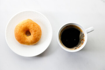 Cup of black coffee, Donut on white marble background. Copy space. Flat lay. Top view.