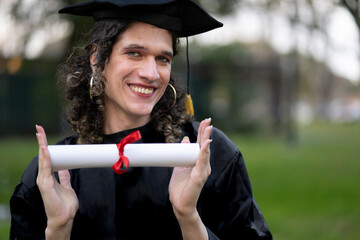Transgender woman recent graduated, dressed in cap and gown, showing off his degree celebrating.