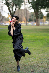 Transgender woman recent graduated, dressed in cap and gown, showing off his degree celebrating.
