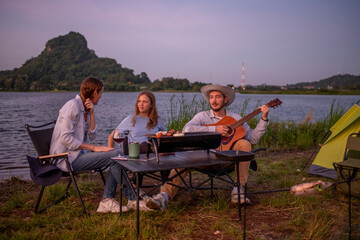 Family camping party with BBQ, and wine by the atmosphere is relaxed, capturing a moment of leisure enjoying a relaxed while sitting on folding chairs around a portable holiday camping.