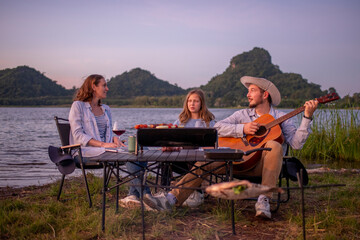 Family camping party with BBQ, and wine by the atmosphere is relaxed, capturing a moment of leisure enjoying a relaxed while sitting on folding chairs around a portable holiday camping.