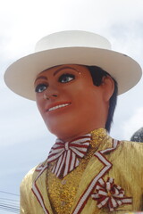 A giant puppet of a man adorned with a hat and a shimmering gold jacket at the Olinda Brazilian Carnival.
