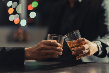 Two young men enjoying a drink during a happy hour sitting at a bar table. Lifestyle, food and drink concept.