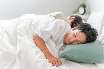 ベッドで眠る若い夫婦（快眠・安眠・熟睡）
