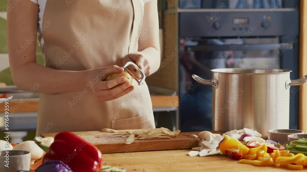 Sticker Close up of woman peeling potatoes with special tool at kitchen