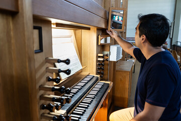 Organist adjusting organ mirror in Catholic Church.