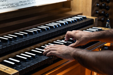 Left side view of Organist's hands playing organ in Catholic Church.