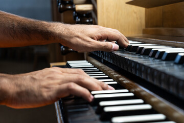 Close-up view of organist's hand playing organ in Catholic Church.